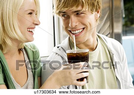 Picture - Young couple sharing a cola drink in a diner . Fotosearch