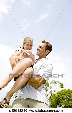 Stock Image - father carrying daughter in his arms. Fotosearch