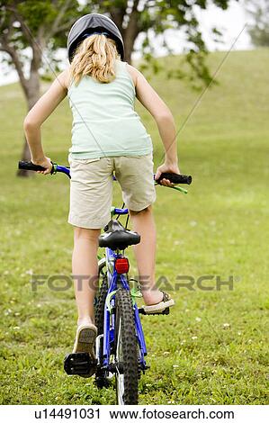 Stock Image - girl riding bicycle on the grass. Fotosearch