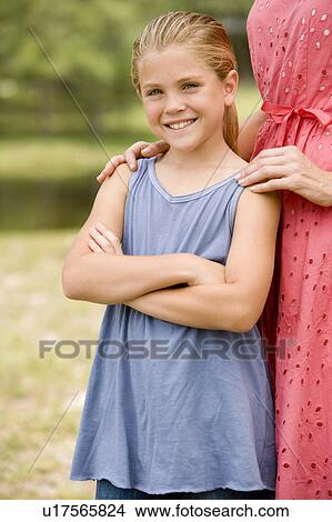 girl standing with woman resting hands on her shoulders View Large Photo Image Picture - girl standing with woman resting hands on her shoulders. Fotosearch