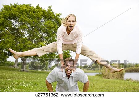 Stock Image - mid adult couple playing leapfrog. Fotosearch