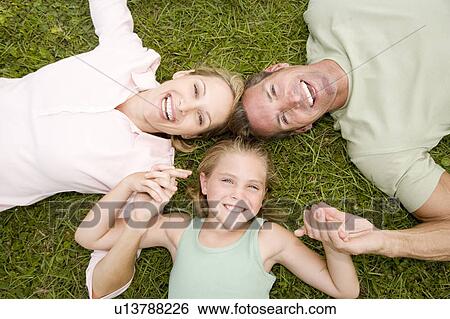 Stock Photograph - portrait family lying on ground head to head . Fotosearch