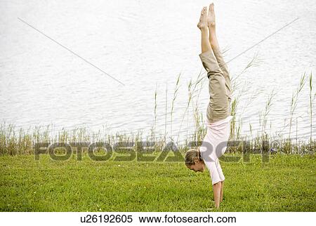 Stock Photography - woman doing a handstand by the waterside. Fotosearch
