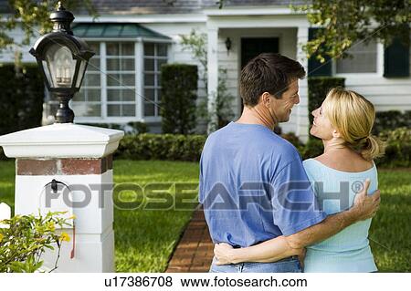Stock Photo - Couple standing on the garden path outside their new home. Fotosearch