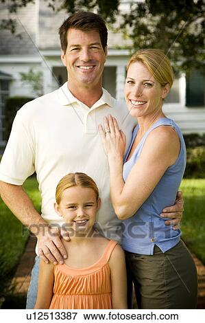 Stock Photo - Family standing on the garden path outside their new home. Fotosearch