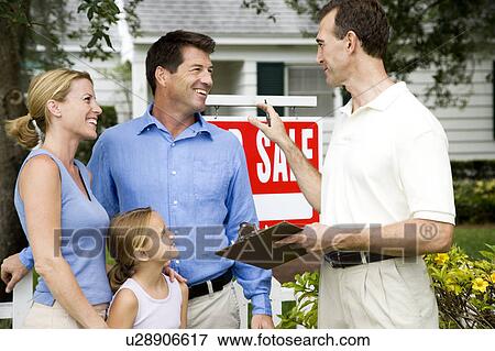 Stock Photo - Family with estate agent outside property for sale. Fotosearch