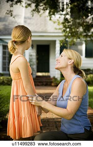 Stock Image - Mother and daughter standing on the garden path outside their new home. Fotosearch