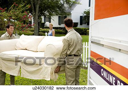 Stock Image - Removal men carrying sofa into new home. Fotosearch
