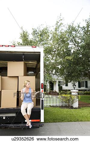 Woman moving home, sitting in the removal van and talking on her mobile phone View Large Photo Image Stock Photograph - Woman moving home, sitting in the removal van and talking on her mobile phone. Fotosearch