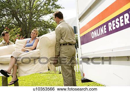 Woman sitting on sofa as removal men carry it into her new home View Large Photo Image Stock Photograph - Woman sitting on sofa as removal men carry it into her new home. Fotosearch