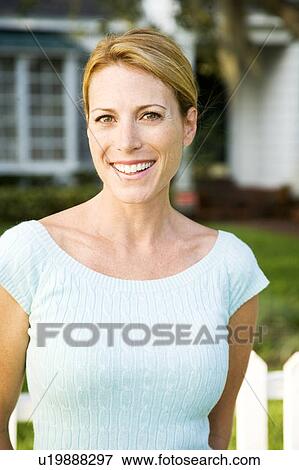 Woman standing by the garden fence outside her new home View Large Photo Image Stock Photo - Woman standing by the garden fence outside her new home. Fotosearch