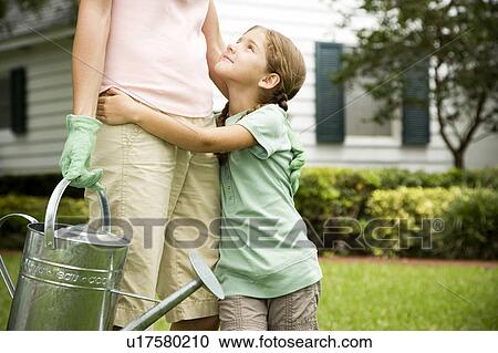 daughter hugging mother carrying watering can View Large Photo Image Stock Image - daughter hugging mother carrying watering can. Fotosearch