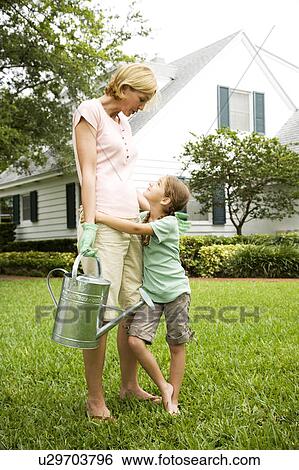 daughter hugging mother carrying watering can View Large Photo Image Stock Photograph - daughter hugging mother carrying watering can. Fotosearch