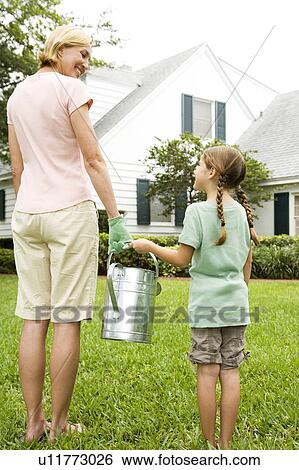 mother and daughter carrying watering can View Large Photo Image Stock Photograph - mother and daughter carrying watering can. Fotosearch