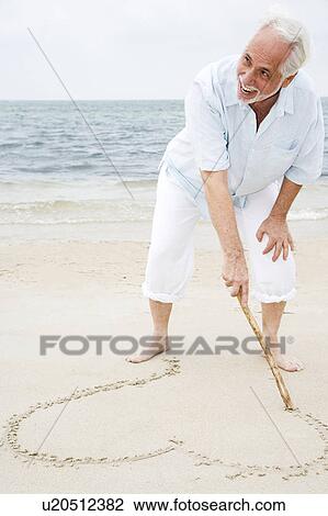 Portrait of a senior man drawing a heart shape in the sand View Large Photo Image Stock Image - Portrait of a senior man drawing a heart shape in the sand. Fotosearch