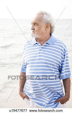Portrait of a senior man standing on a beach looking thoughtful View Large Photo Image Stock Photo - Portrait of a senior man standing on a beach looking thoughtful. Fotosearch