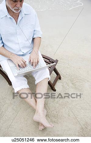 Senior man at the beach using a laptop computer View Large Photo Image Stock Photograph - Senior man at the beach using a laptop computer. Fotosearch