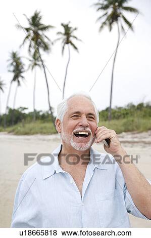 Stock Photo - Senior man on a mobile telephone at the beach . Fotosearch