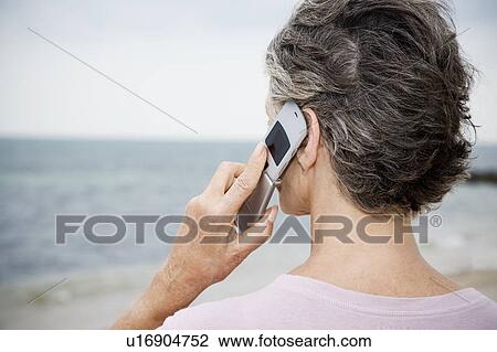 Senior woman using a mobile telephone at the beach View Large Photo Image Stock Image - Senior woman using a mobile telephone at the beach . Fotosearch