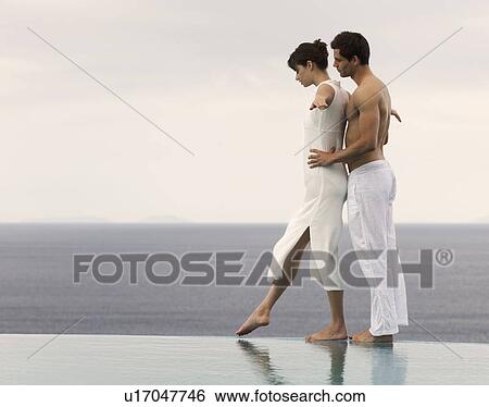 Stock Photograph - A couple balancing at the edge of a pool. Fotosearch
