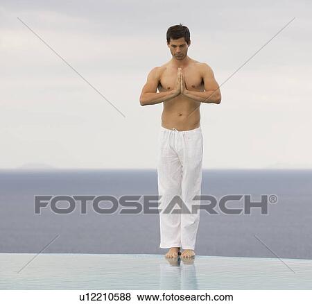 Stock Photo - A man meditating at the edge of a pool. Fotosearch