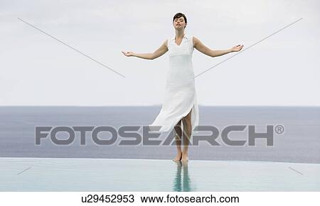 Stock Image - A woman meditating by a pool. Fotosearch