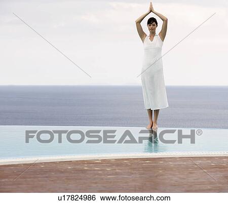 Stock Photograph - A woman meditating by a pool. Fotosearch