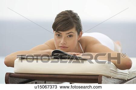 Stock Image - A woman relaxing on a sun lounger. Fotosearch