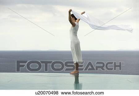 Stock Photo - A woman standing in the breeze by a pool. Fotosearch