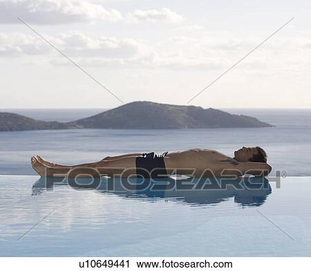 Stock Image - A man relaxing by a pool. Fotosearch