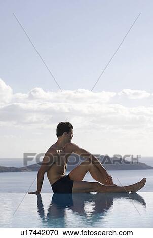 Stock Image - A man relaxing by a pool. Fotosearch