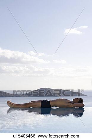 Stock Photograph - A man relaxing by a pool. Fotosearch