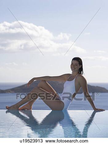 Stock Image - A woman relaxing by a pool. Fotosearch