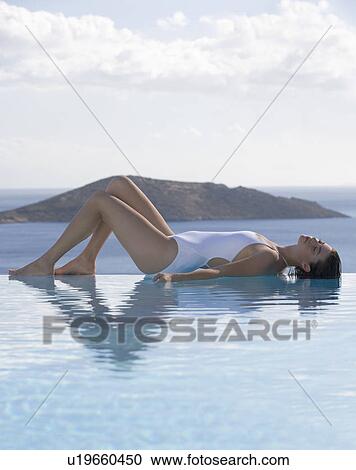 Stock Image - A woman relaxing by a pool. Fotosearch