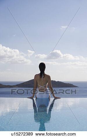 Stock Photo - A woman relaxing by a pool. Fotosearch
