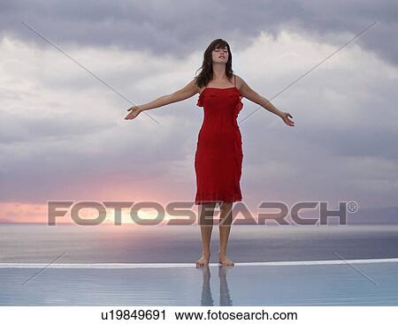 A woman standing on the edge of a pool at sunset View Large Photo Image Stock Image - A woman standing on the edge of a pool at sunset. Fotosearch