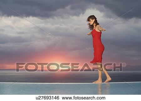 A woman walking along the edge of a pool at sunset View Large Photo Image Stock Photograph - A woman walking along the edge of a pool at sunset. Fotosearch