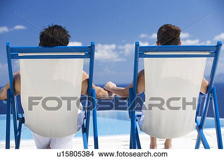Picture - A couple relaxing in deck chairs. Fotosearch