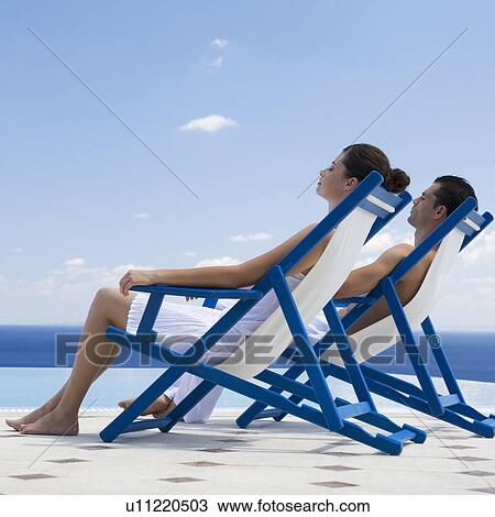 A couple relaxing in deck chairs View Large Photo Image Stock Image - A couple relaxing in deck chairs. Fotosearch