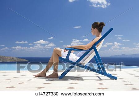 Stock Image - A woman relaxing in a deck chair. Fotosearch