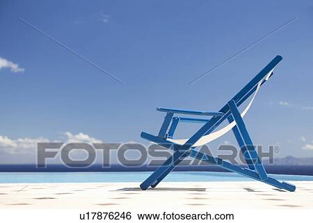 Stock Photograph - An empty deck chair by a pool. Fotosearch