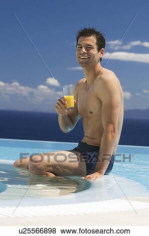 A man drinking fruit juice by a pool View Large Photo Image Stock Photo - A man drinking fruit juice by a pool. Fotosearch
