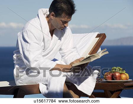 Picture - A man reading a book by a pool. Fotosearch