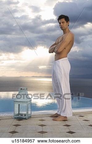 Stock Photo - A man standing by a pool in the evening. Fotosearch