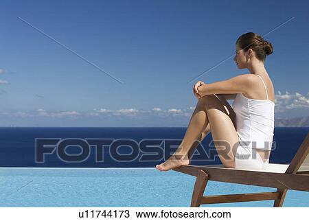 Stock Image - A woman relaxing by a pool. Fotosearch