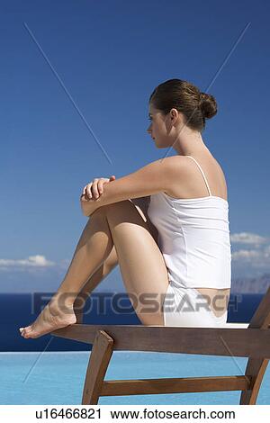 Stock Image - A woman relaxing by a pool. Fotosearch
