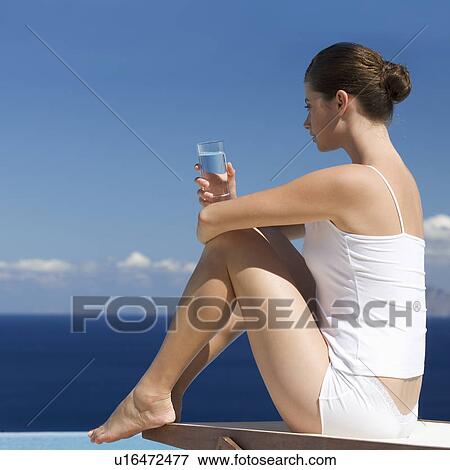 Stock Photo - A woman relaxing by a pool. Fotosearch