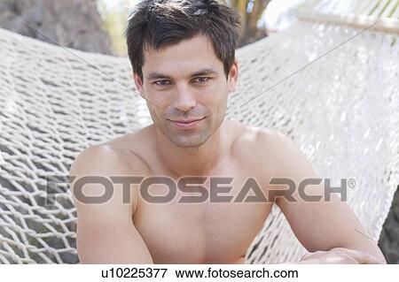 A man sitting in a hammock View Large Photo Image Stock Photo - A man sitting in a hammock. Fotosearch
