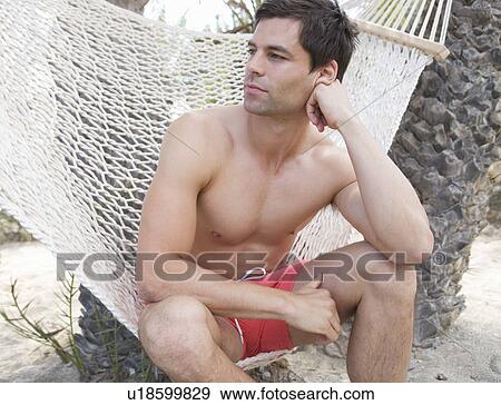 A man sitting in a hammock View Large Photo Image Stock Photo - A man sitting in a hammock. Fotosearch