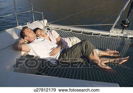 Stock Photo - A couple lying on a catamaran. Fotosearch